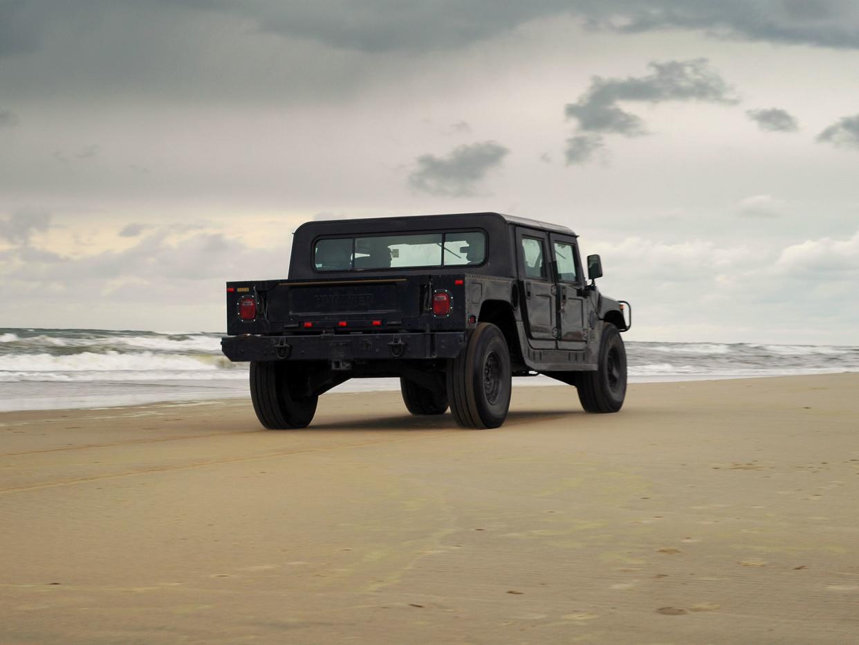 Noordwijk, The Netherlands-June 19, 2004: Two people in a black Hummer H1 SUV are driving on a beach on a cloudy day.