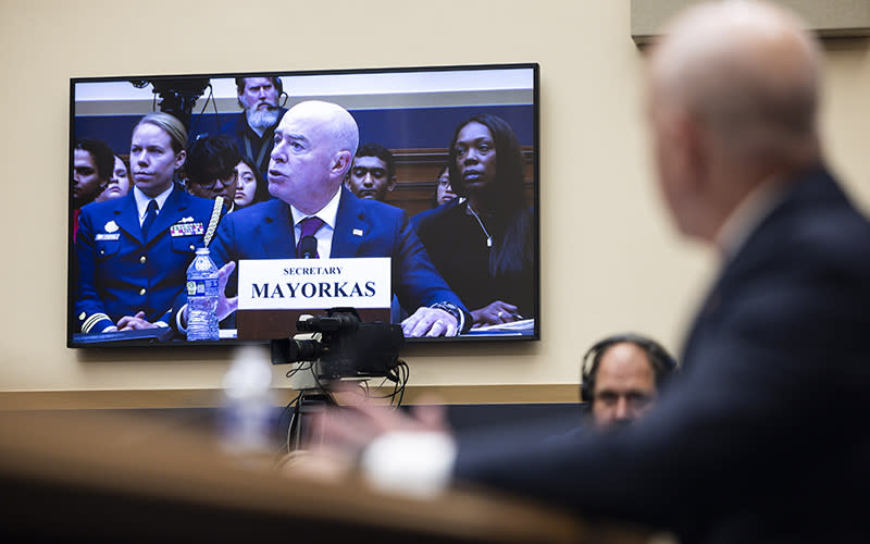 Secretary Alejandro Mayorkas is seen on a TV in the background as he testifies