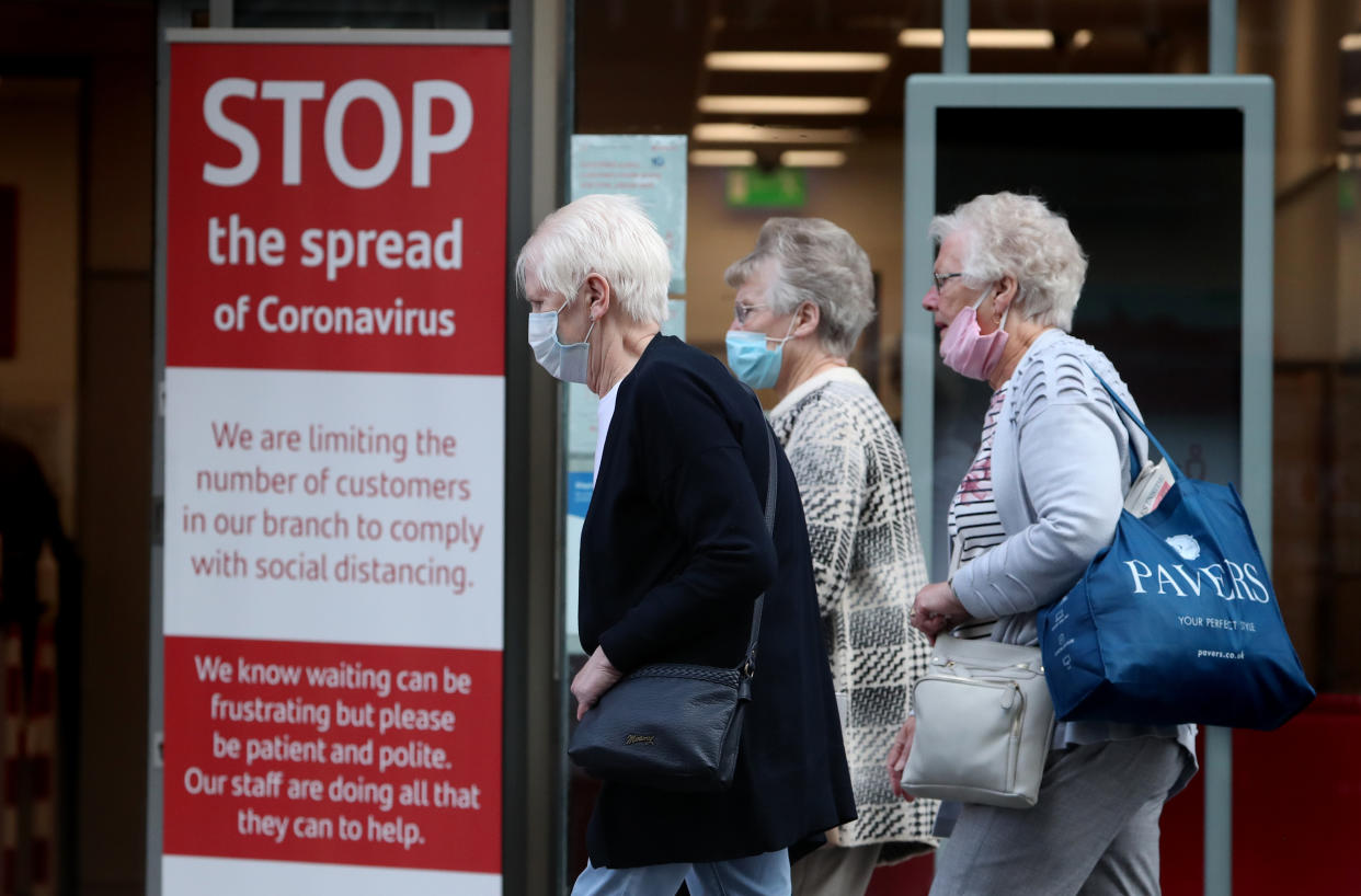 Members of the public wearing face masks walk passed a sign in a bank window in Glasgow. (Photo by Andrew Milligan/PA Images via Getty Images)