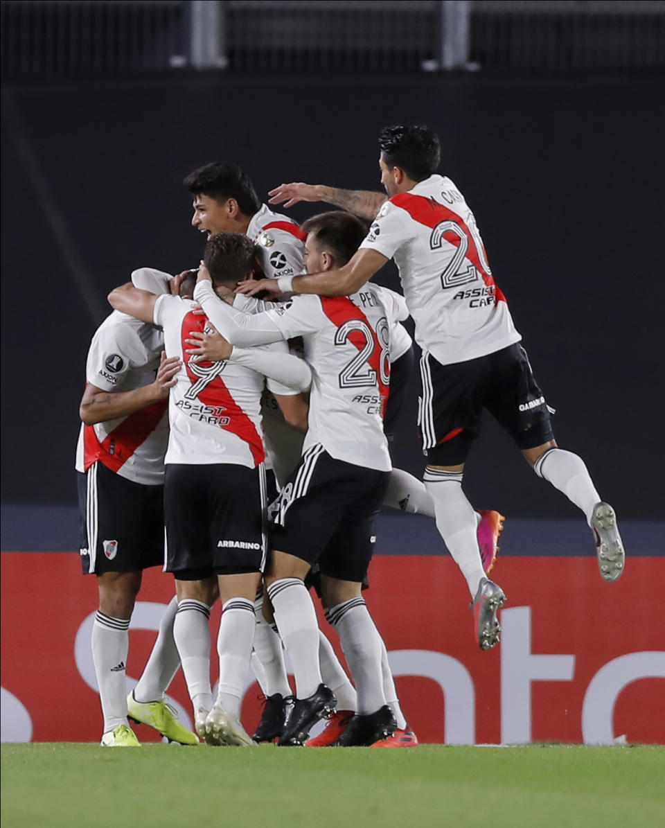 Fabrizio German Angileri of Argentina's River Plate, left, is congratulated by his teammates after he scored the opening goal against Colombia's Independiente Santa Fe during a Copa Libertadores soccer match in Buenos Aires, Argentina, Wednesday, May 19, 2021. (Juan Ignacio Roncoroni/Pool via AP)