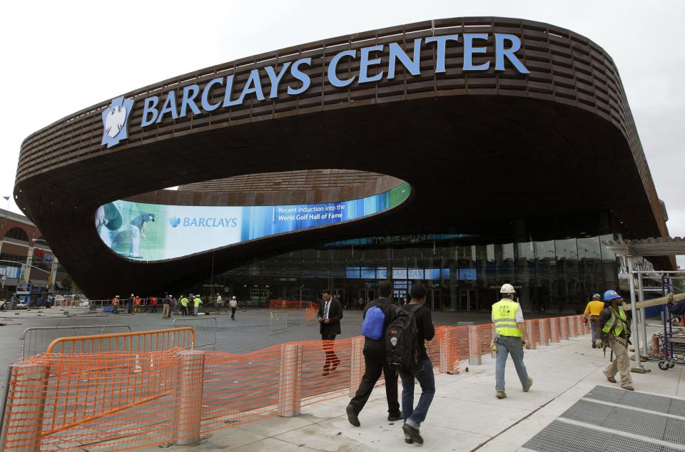 Pedestrians pass the main entrance to the Barclays Arena in New York, Thursday, Sept. 20, 2012 as workmen complete their cleanup for Friday's ribbon-cutting ceremony. A new chapter in Brooklyn's history Friday when the Brooklyn Nets new arena will open, just across the street from the spot where the Dodgers owner once tried to build a baseball stadium that never saw the light of day. (AP Photo/Kathy Willens)