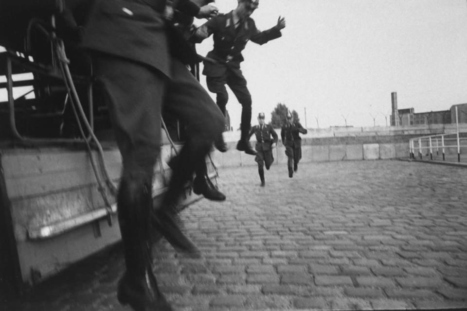 Three West Berlin police officers jump off a truck as two others run to meet them before starting their shifts on guard duty at the Berlin Wall in October 1961. (Paul Schutzer—Time & Life Pictures/Getty Images) <br> <br> <a href="http://life.time.com/history/berlin-wall-photos-early-days-of-the-cold-war/#1" rel="nofollow noopener" target="_blank" data-ylk="slk:Click here to see the full collection at LIFE.com;elm:context_link;itc:0;sec:content-canvas" class="link ">Click here to see the full collection at LIFE.com</a>