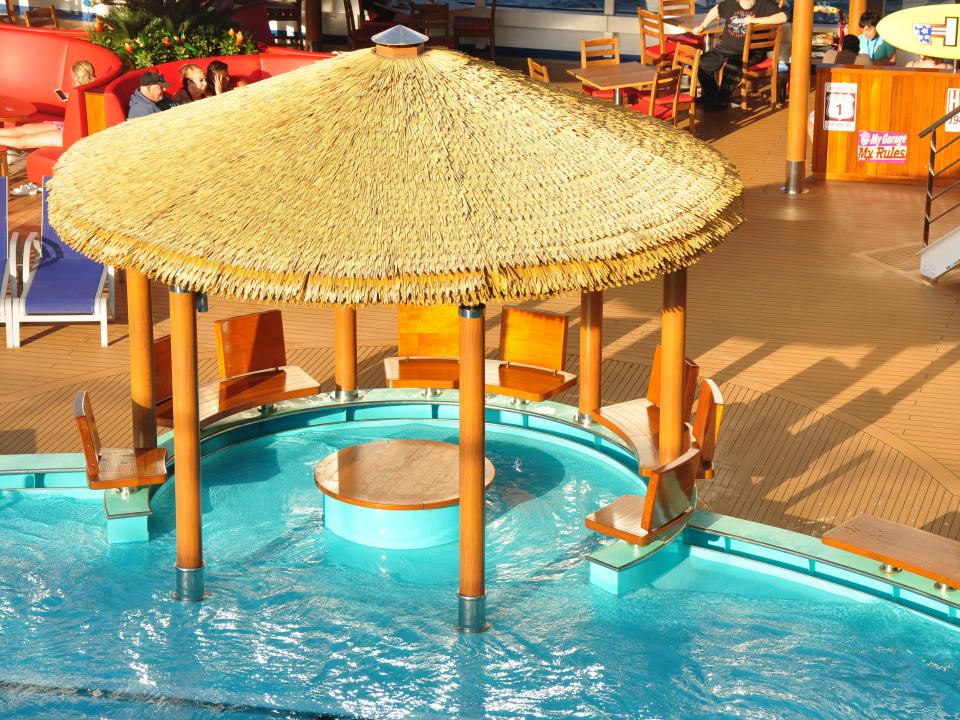 A thatched roof cabana in the pool of a cruise ship.