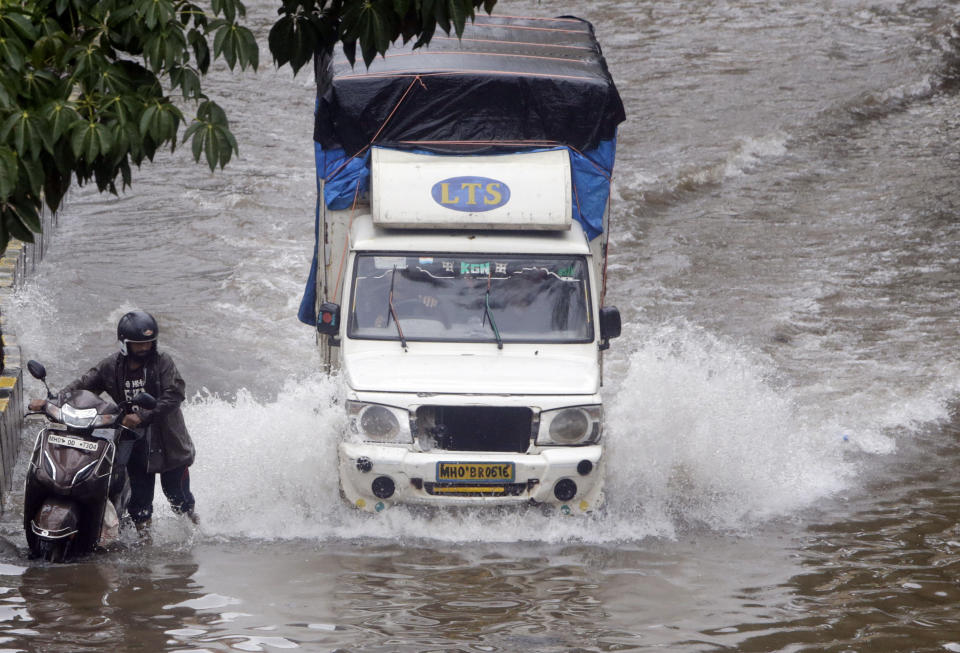 A man pushes his scooter through a waterlogged street following heavy rains in Mumbai, India, Tuesday, July 2, 2019. Heavy monsoon rains in western India caused at least three walls to collapse onto huts and city shanties, killing more than two dozen people and injuring dozens of others, officials said Tuesday, as forecasters warned of more rains. (AP Photo/Rajanish Kakade)