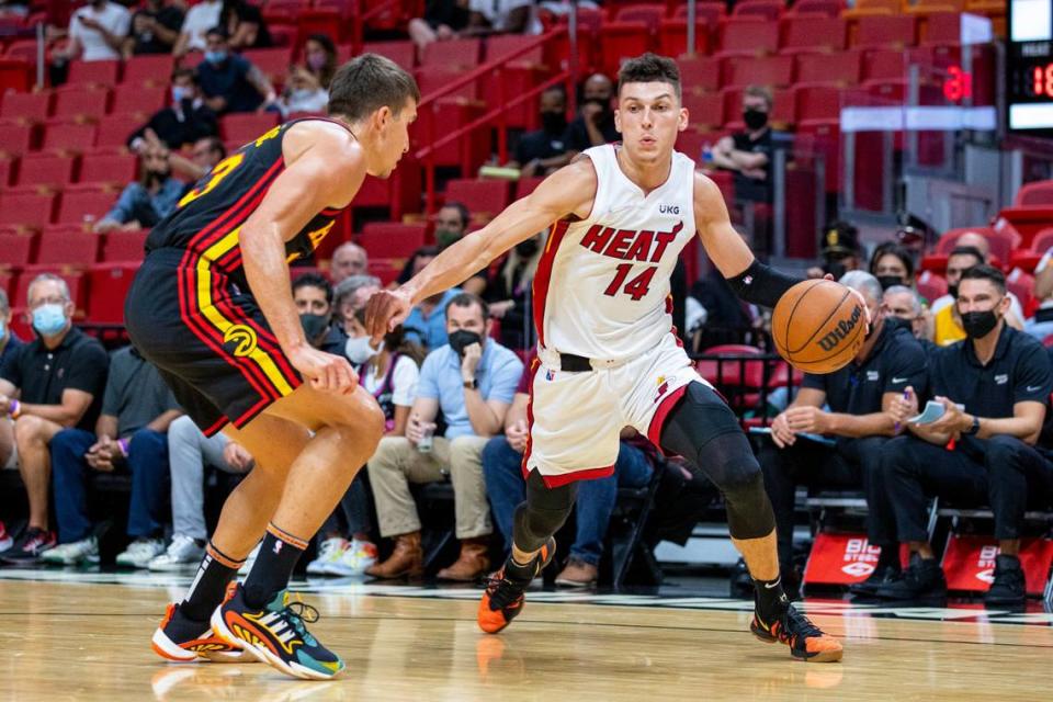 Miami Heat guard Tyler Herro (13) dribbles over Atlanta Hawks guard Bogdon Bogdanovic (13) during the first quarter of an NBA game at FTX Arena in Miami, Florida, on Monday, October 4, 2021.