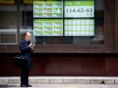 A man stands in front of electronic boards showing stock prices and exchange rate between Japanese Yen and U.S dollar outside a brokerage in Tokyo, Japan, January 20, 2017. REUTERS/Kim Kyung-Hoon