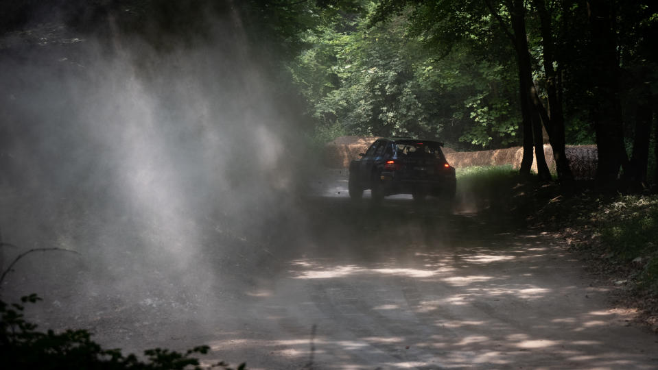 A rally car turning the corner of a race track at Goodwood