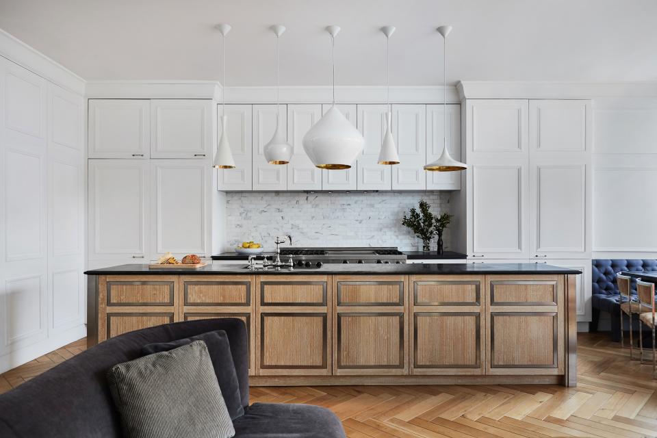 The cabinetry and all the walls have the same molding in order to convey a sense of continuity throughout the apartment. The herringbone floors and chalky white paint make Blinken “feel like I’m in Paris.” The focal point of the kitchen is the array of Tom Dixon lights.