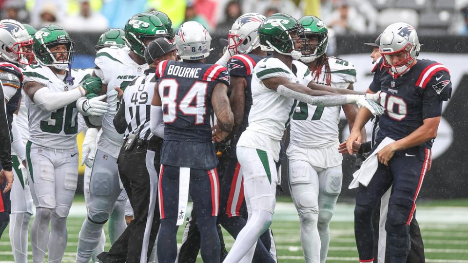 Jets cornerback Sauce Gardner (1) pushes New England Patriots quarterback Mac Jones (10) behind a group of players during the second half at MetLife Stadium