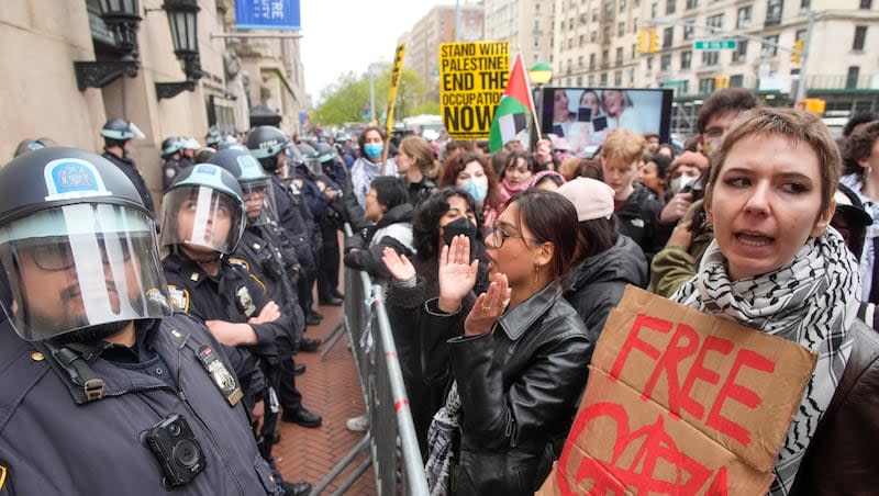 Police in riot gear stand guard as demonstrators chant slogans outside the Columbia University campus, Thursday, April 18, 2024, in New York. U.S. colleges and universities are preparing for end-of-year commencement ceremonies with a unique challenge: providing safety for graduates while honoring the free speech rights of students involved in protests over the Israel-Hamas war.