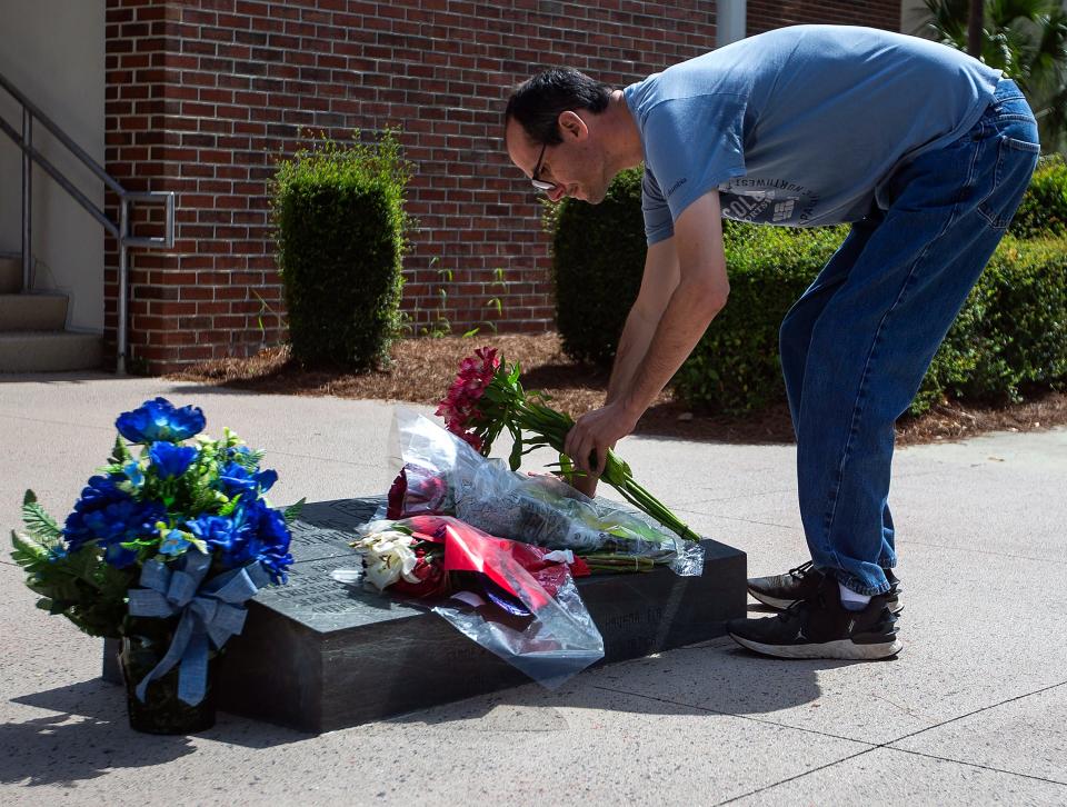 Spencer Walling places flowers on a memorial for fallen officers outside the Tallahassee Police Department on Thursday, June 9, 2022, a day after a 34-year-old officer was killed on duty. 