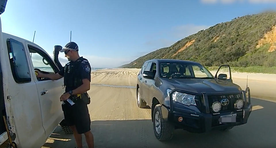 A cop stopping and speaking to the driver of a white ute on a Queensland beach. Source: Queensland Police