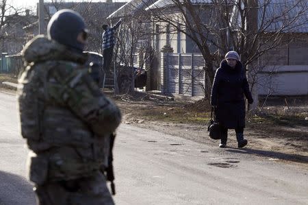 A local resident walks along a street, with a member of the Ukrainian armed forces seen in the foreground, in the settlement of Velyka Novosilka, Donetsk region, February 24, 2015. REUTERS/Valentyn Ogirenko