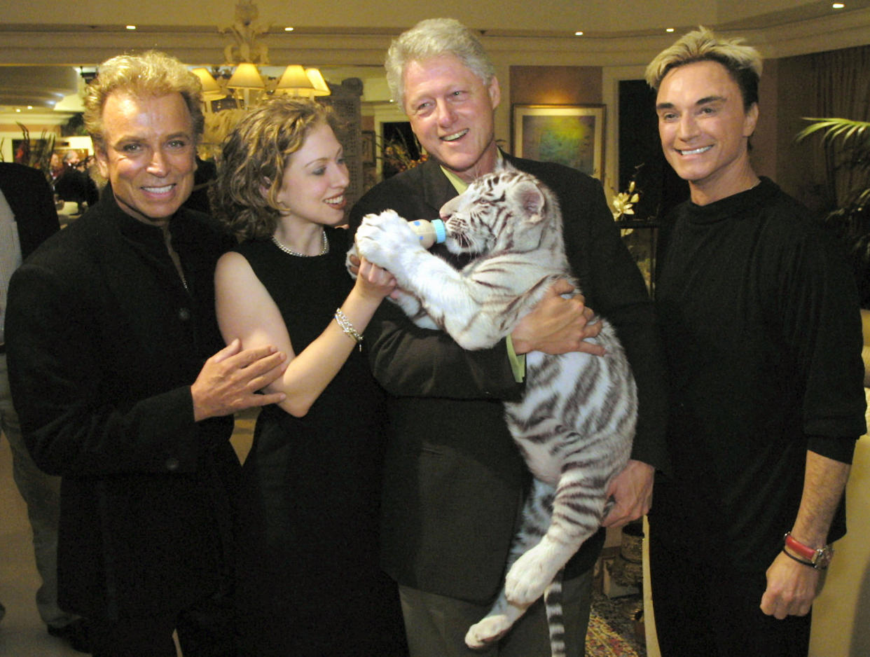 Chelsea Clinton holds a bottle for a white tiger cub held by her father, former President Bill Clinton, alongside Siegfried and Roy after a performance at the Mirage in 2001.