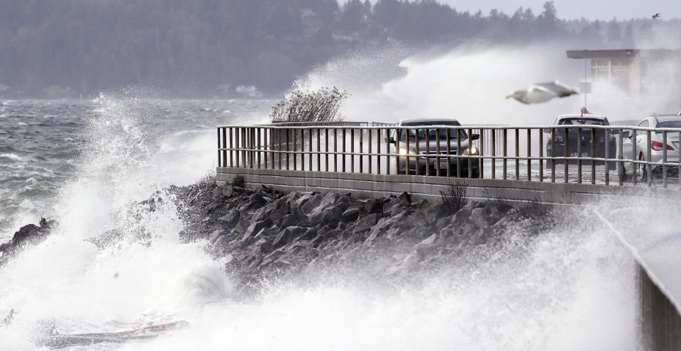 Waves crash against a seawall at high tide as cars maneuver past during a windstorm Thursday, Dec. 20, 2018, in Seattle. More than 140,000 households and businesses lost power Thursday as strong winds toppled trees, closed roads and even trapped a trampoline between power lines in western Washington. A high wind warning remained in effect for much of area into Thursday evening, with gusts up to 60 miles an hour recorded earlier in the day. (AP Photo/Elaine Thompson)