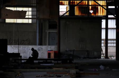 An Afghan immigrant is sits inside a wood factory across the street from a ferry terminal in the western Greek town of Patras April 28, 2015. REUTERS/Yannis Behrakis