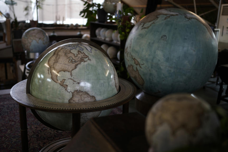 Various size of globes are displayed at a studio in London, Tuesday, Feb. 27, 2024. Globes in the age of Google Earth capture the imagination and serve as snapshots of how the owners see the world and their place in it. Peter Bellerby made his first globe for his father, after he could not find one accurate or attractive enough. In 2008, he founded Bellerby & Co. Globemakers in London. His team of dozens of artists and cartographers has made thousands of bespoke globes up to 50 inches in diameter. The most ornate can cost six figures. (AP Photo/Kin Cheung)