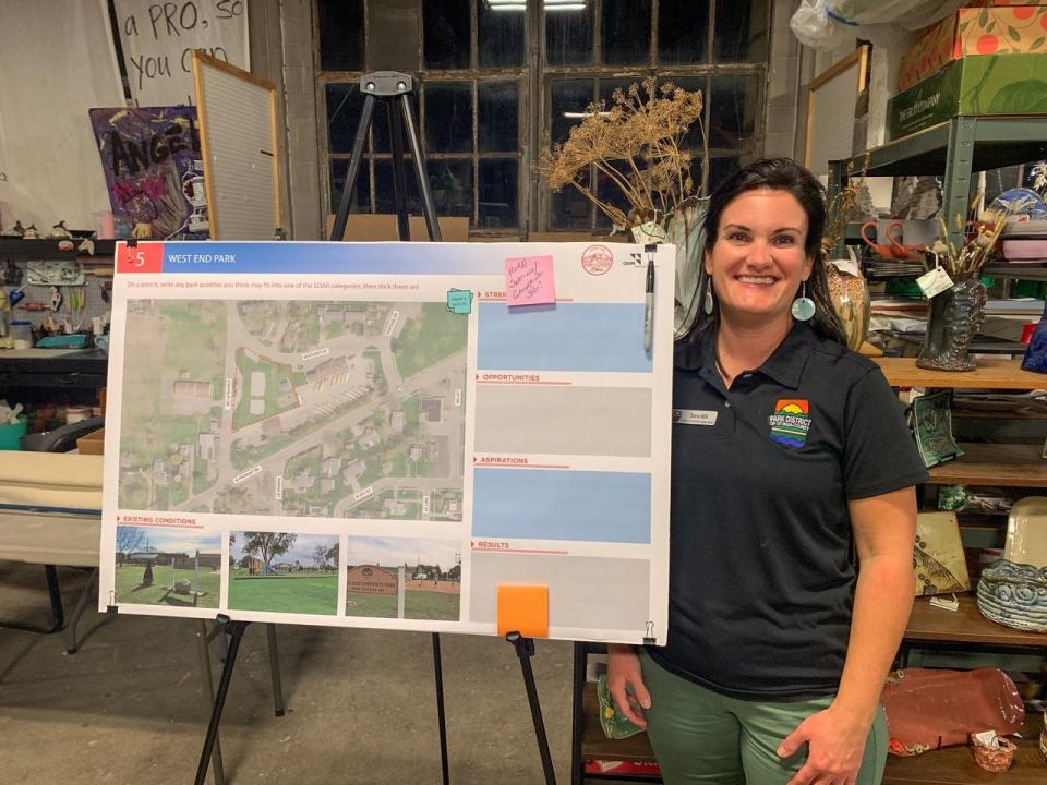 Sara Hill, an administrative specialist with the Park District of Ottawa County, stands next to a display board of West End Park.