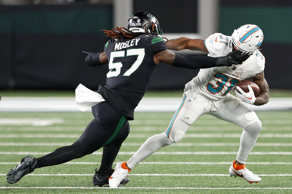 Miami Dolphins running back Raheem Mostert (31) avoids a tackle by New York Jets linebacker C.J. Mosley (57) during the third quarter of an NFL football game, Friday, Nov. 24, 2023, in East Rutherford, N.J. (AP Photo/Noah K. Murray)