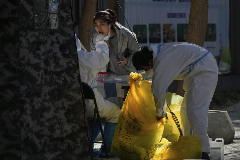 A worker in protective suit collects a sample from a woman at a coronavirus testing site inside a residential compound in Beijing, Tuesday, Nov. 15, 2022. China's ruling party called for strict adherence to the hard-line "zero-COVID" policy Tuesday in an apparent attempt to guide public perceptions after regulations were eased slightly in places. (AP Photo/Andy Wong)