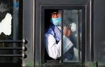 A man wearing a protective mask sits inside a bus that will take him to a quarantine facility, amid concerns about the spread of coronavirus disease (COVID-19), in Nizamuddin area of New Delhi,