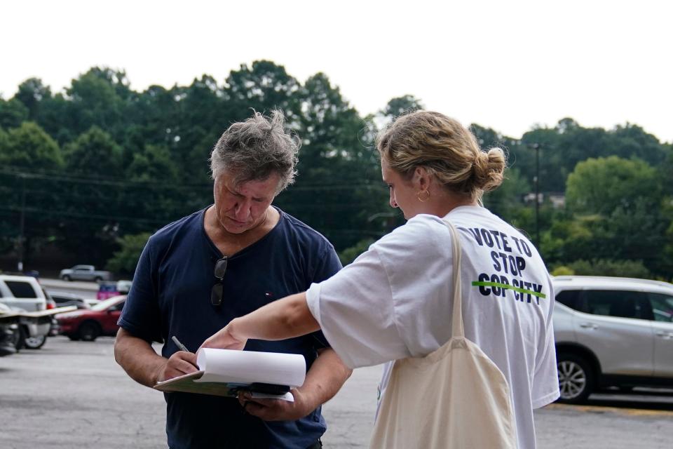 Canvasser Sienna Giraldi, 26, right, with Stop Cop City Vote Coalition, talks to an Atlanta resident, left, on July 20 in Atlanta. Georgia activists are furious that Democratic senators haven’t condemned Atlanta officials’ plan to verify every signature on a petition to force a vote on a proposed police and firefighting training center.