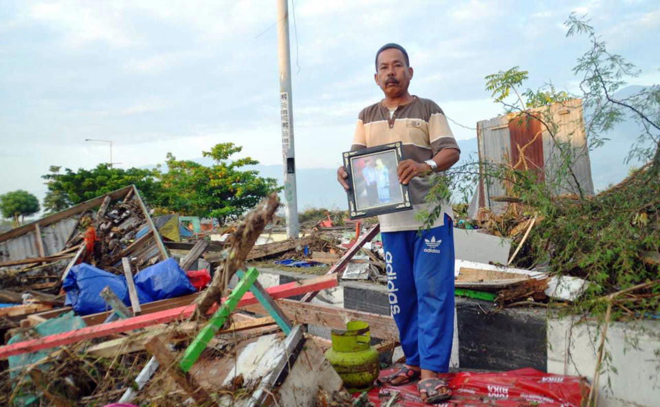 A man holds a family picture retrieved from a damaged house following a massive earthquake and tsunami in Palu, Central Sulawesi, Indonesia, Sunday, Sept. 30, 2018. Rescuers were scrambling Sunday to try to find trapped victims in collapsed buildings where voices could be heard screaming for help after a massive earthquake in Indonesia spawned a deadly tsunami two days ago. (AP Photo/Rifki)