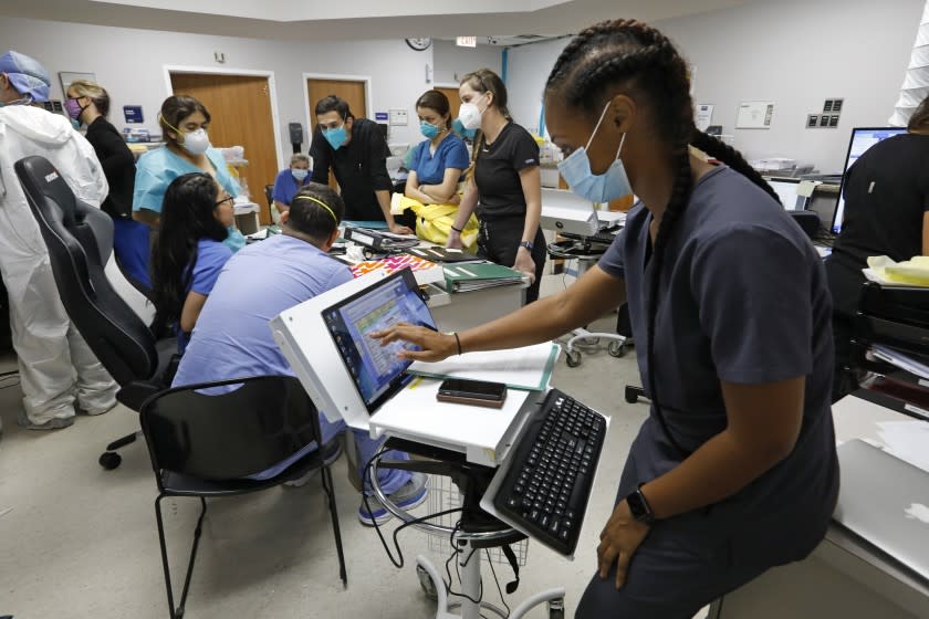 HOUSTON, TEXAS-JULY 1, 2020-Medical students and staff members on the COVID-19 ward at United Memorial Medical Center gather to go over patients' status at the start of their shift. Jasmine Campbell, 29, at right, said that as a medical student, working the COVID unit, "keeps you on your toes." At United Memorial Medical Center in Houston, Texas, the staff works together as a team to save lives. At United Memorial Medical Center in Houston, Texas, Dr. Joseph Varon leads a team to fight the increasing number of coronavirus patients in the expanded Covid-19 ward on July 1, 2020. (Carolyn Cole/Los Angeles Times)