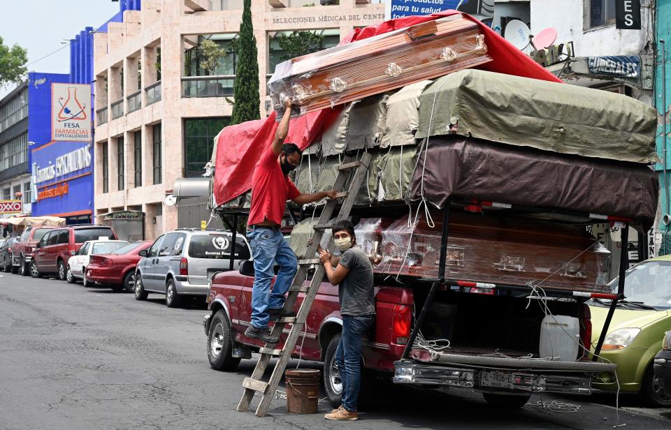 Workers unload coffins from a truck outside a funeral home located in front of the General Hospital in Mexico City on August 20, 2020 amid the COVID-19 coronavirus pandemic. (Photo by ALFREDO ESTRELLA / AFP) (Photo by ALFREDO ESTRELLA/AFP via Getty Images)