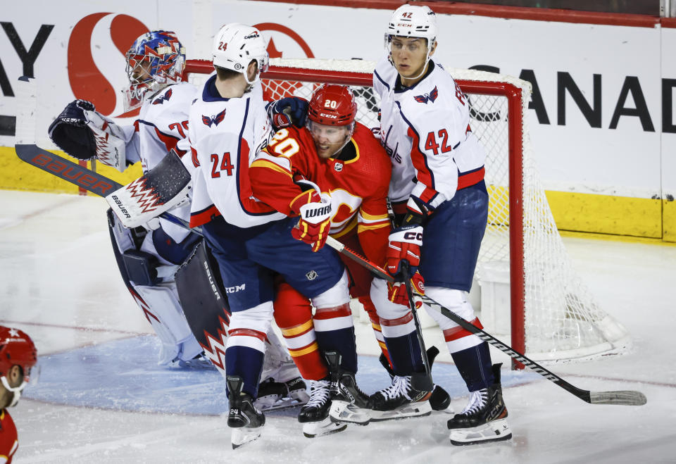 Washington Capitals forward Connor McMichael (24) and defenseman Martin Fehervary (42) check Calgary Flames forward Blake Coleman (20) as goalie Charlie Lindgren (79) follows the play during the second period of an NHL hockey game in Calgary, Alberta, Monday, March 18, 2024. (Jeff McIntosh/The Canadian Press via AP)