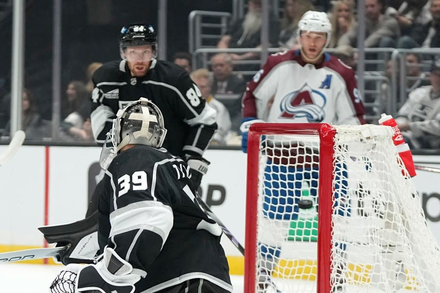Los Angeles Kings goaltender Cam Talbot, left, is scored on by Colorado Avalanche center Nathan MacKinnon as defenseman Vladislav Gavrikov, center, and right wing Mikko Rantanen watch during the first period of an NHL hockey game Wednesday, Oct. 11, 2023, in Los Angeles. (AP Photo/Mark J. Terrill)