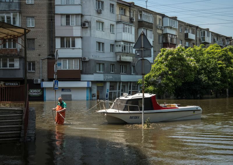 A man moors a boat at a flooded street during an evacuation from a flooded area after the Nova Kakhovka dam breached in Kherson