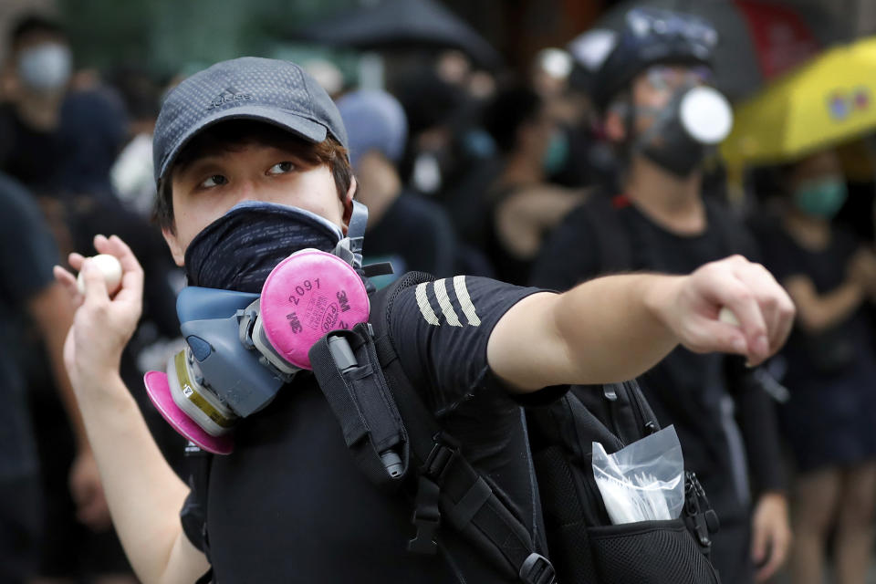 A protester throws an egg to the Tseung Kwan O police station during an anti-extradition bill protest in Hong Kong, Sunday, Aug. 4, 2019. Protesters held two more rallies Sunday after Hong Kong police announced more than 20 people were arrested following clashes at an earlier demonstration, adding to increasingly tense confrontations with the Chinese territory's government. (AP Photo/Vincent Thian)
