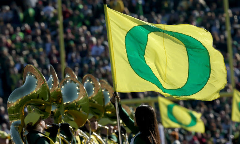 An Oregon band member holding a school flag.