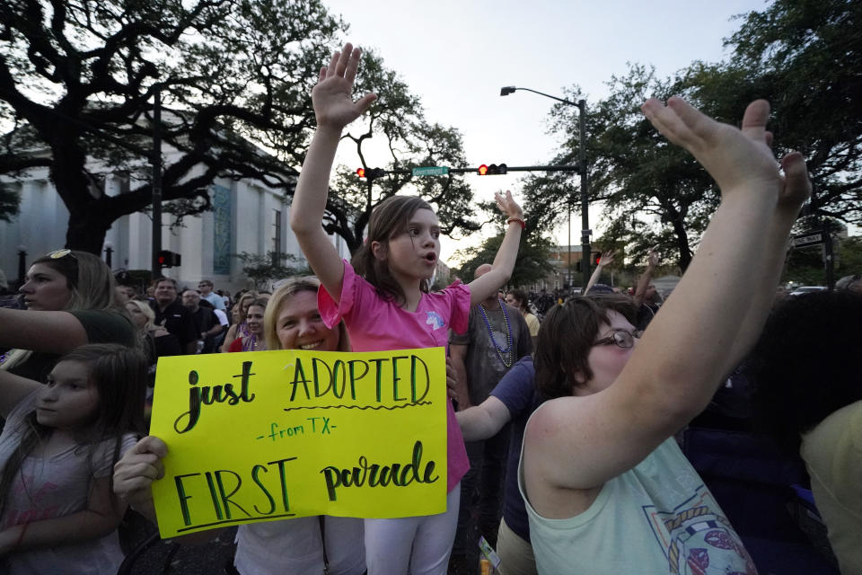 Bobbi Bailey, left, holds a sign with her daughter Codi Bailey, 8, who was adopted eight months ago, during a parade dubbed "Tardy Gras," to compensate for a cancelled Mardi Gras due to the COVID-19 pandemic, in Mobile, Ala., Friday, May 21, 2021. (AP Photo/Gerald Herbert)