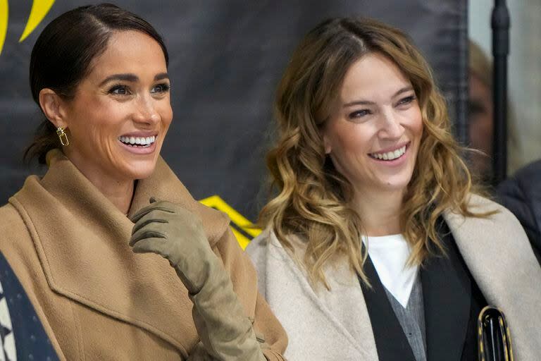 Meghan Markle y Luisana Lopilato sonríen mientras observan a sus respectivos esposos, el Príncipe Harry y Michael Bublé, participar en los Invictus Games