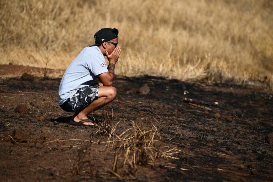 Maui resident John Rey Serrano reacts while looking from a road above Lahaina Town in the aftermath of a wildfire in Lahaina, western Maui, Hawaii.