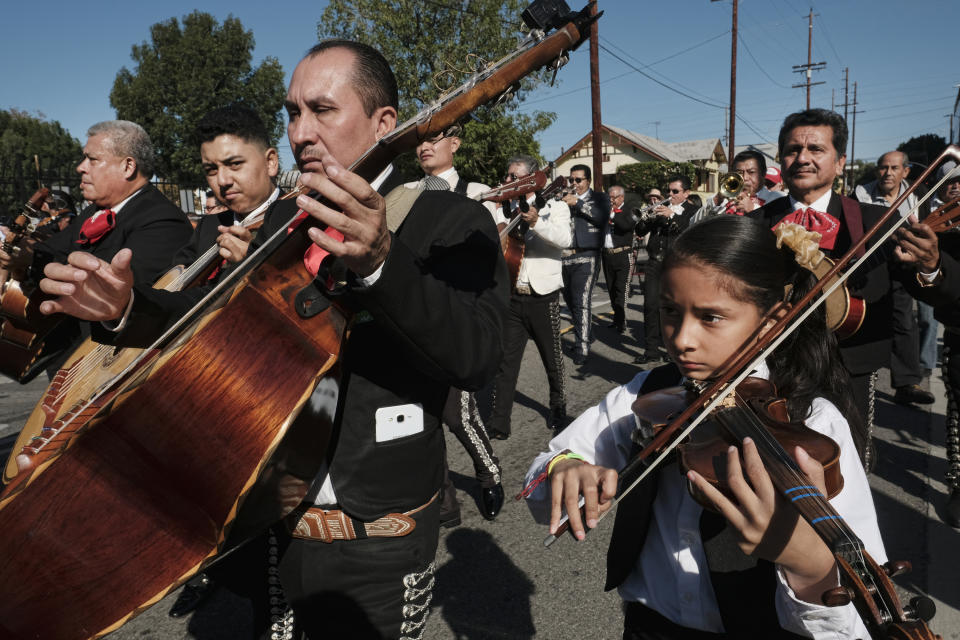 FILE - Mariachis play in the street during the Santa Cecilia procession in the Boyle Heights section of Los Angeles on Tuesday, Nov. 22, 2016. With the blasting of trumpets and the strumming of guitars, the U.S. Postal Service is celebrating the release of a new series of stamps honoring the traditional Mexican genre of mariachi. The first-day-of-issue ceremony was held Friday, July 15, 2022, in New Mexico's largest city during the 30th annual Mariachi Spectacular de Albuquerque. (AP Photo/Richard Vogel, File)