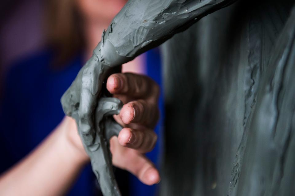 Sculptor Jane DeDecker touches up the scaled clay model of her piece "Every Word We Utter" as she works on building out the foam and metal structure of the full-sized clay model on Friday, March 29, 2019, at her studio in Loveland, Colo. 