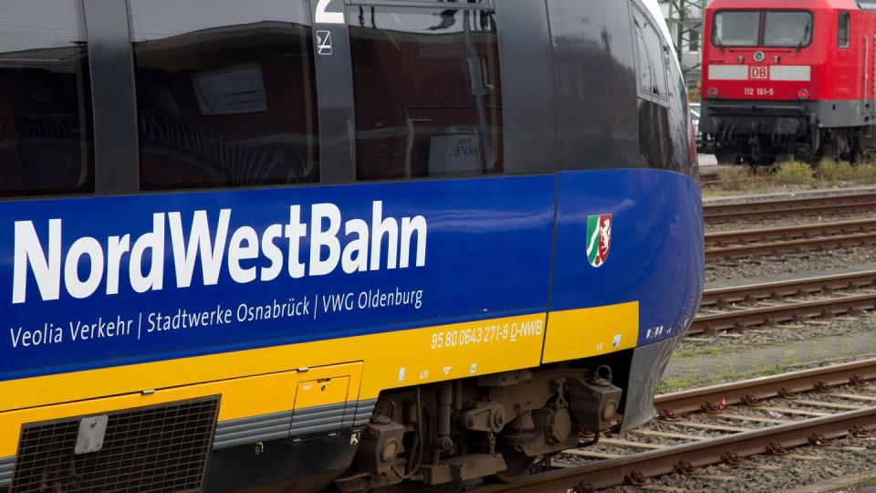 Ein Triebwagen der NordWestBahn steht auf dem Hauptbahnhof in Münster vor einer Lok der Deutschen Bahn.