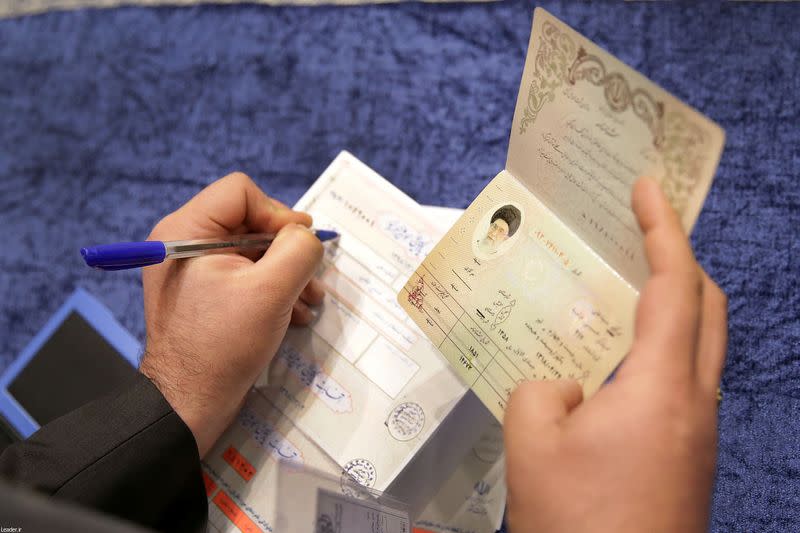 Poll worker checks the ID of Iran's Supreme Leader Ayatollah Ali Khamenei who has arrived to cast his vote at a polling station during parliamentary elections in Tehran