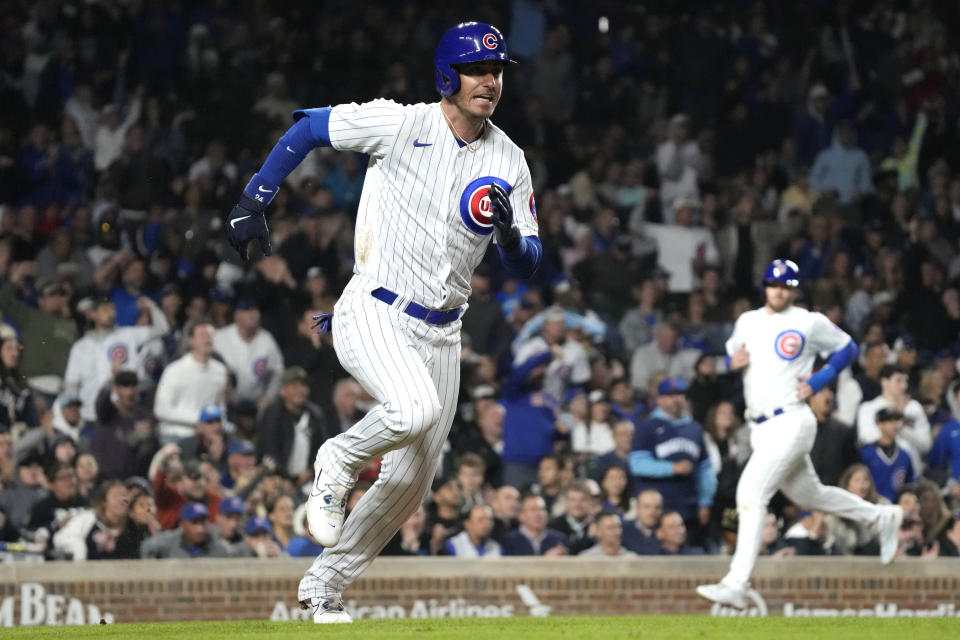 Chicago Cubs' Cody Bellinger, left, runs after hitting a one-run double as Ian Happ, right, scores during the fifth inning of a baseball game against the Pittsburgh Pirates in Chicago, Thursday, June 15, 2023. (AP Photo/Nam Y. Huh)