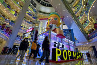 Shoppers wearing face masks to help curb the spread of the coronavirus wall by the Chinese toy maker POP Mart display booth at a shopping mall in Beijing on Dec. 9, 2020. China's economy grew 2.3% in 2020 as a recovery from the coronavirus pandemic accelerated while the United States, Europe and Japan struggled with disease flare-ups. (AP Photo/Andy Wong)