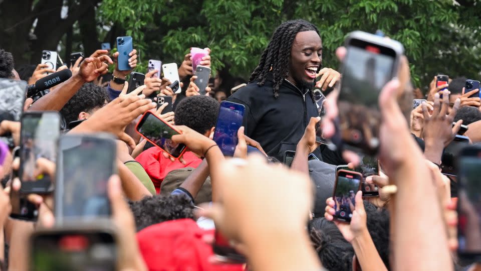 People gather around and cheer for Kai Cenat (C) as members of the NYPD respond to thousands of people gathered for a "giveaway" event on August 4, 2023 in New York City.  - Alexi J. Rosenfeld/Getty Images