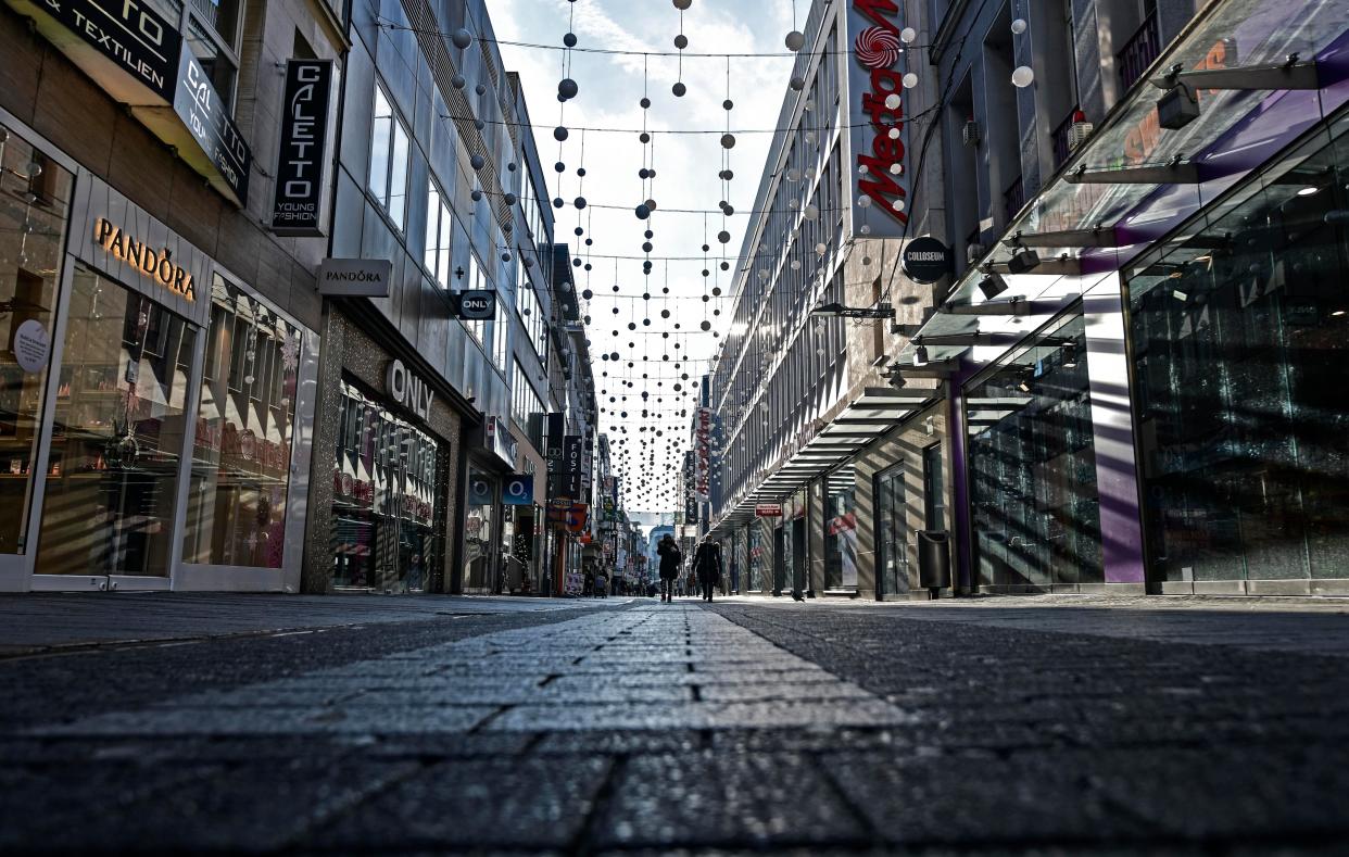 People walk in a shopping road in Cologne, Germany on Wednesday, Dec. 16, 2020. Germany has entered a harder lockdown, closing shops and schools in an effort to bring down stubbornly high new cases of the coronavirus.