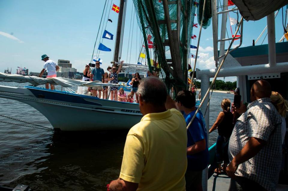 People on the Blessing Boat wave to another boat as it pulls alongside to receive a blessing from Msgr. Dominick Fullam during the Blessing of the Fleet in Biloxi on Sunday, May 28, 2023.