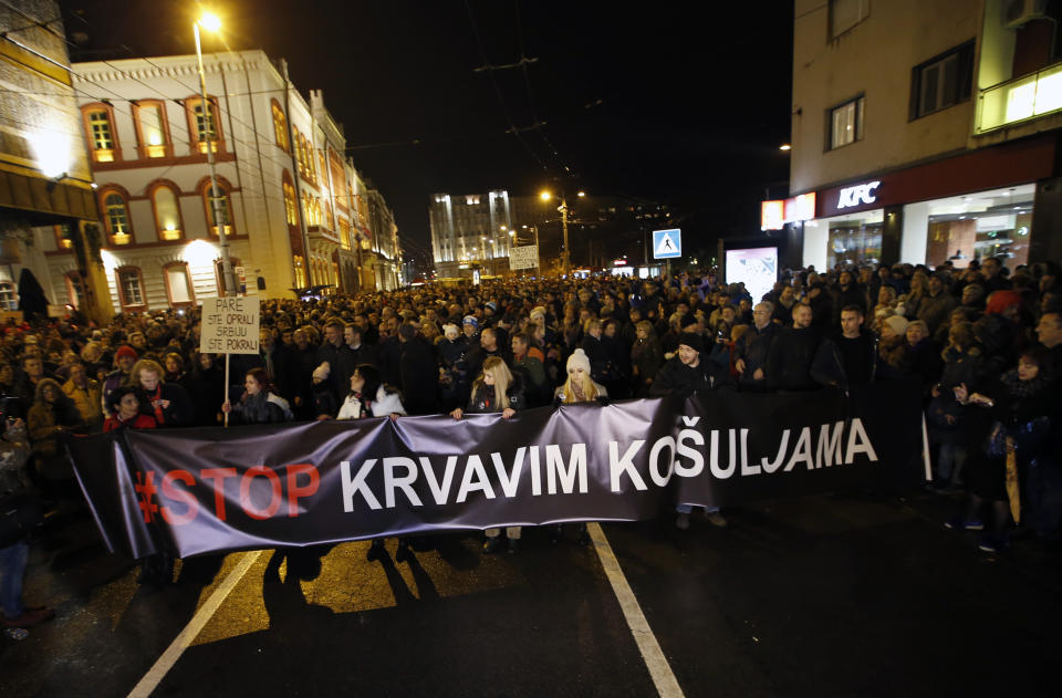 People hold a banner that reads: ''Stop to bloody shirts'' during a protest in Belgrade, Serbia, Saturday, Dec. 8, 2018. Thousands of people marched in Serbia against the autocratic rule of President Aleksandar Vucic and his government. An opposition alliance called the protest on Saturday after assailants recently beat up and seriously injured a leftist party leader and his associates in a southern Serbian city. (AP Photo/Darko Vojinovic)