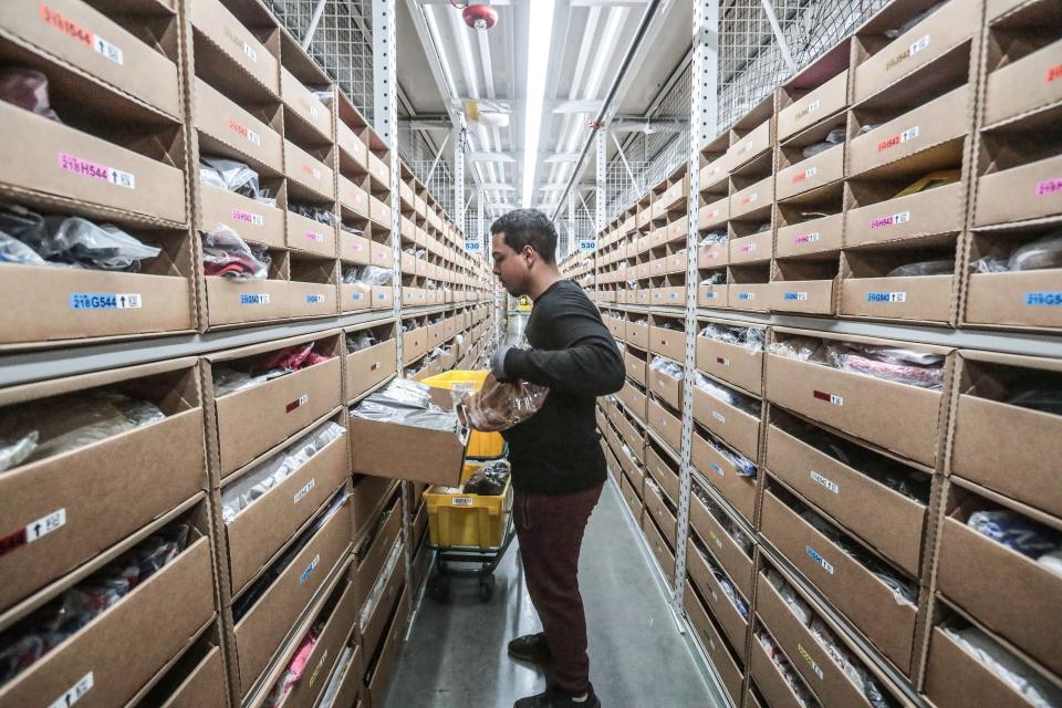 Kevin Johnson, a member of the pick-team at the Amazon Fulfillment Center in Moreno Valley, Calif., takes items from shelves and places them into the yellow bins to fill orders on Thursday, December 13, 2018.