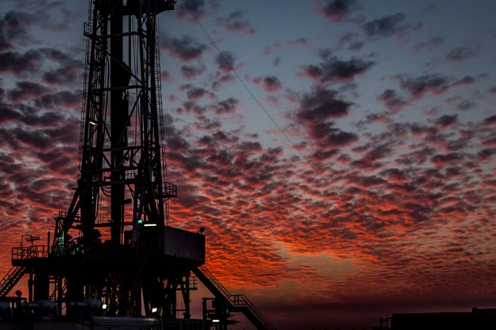 A drilling rig with red and orange clouds in the background.