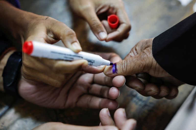 Officials mark the thumb of a voter with ink during the casting of vote in the 12th general election in Dhaka